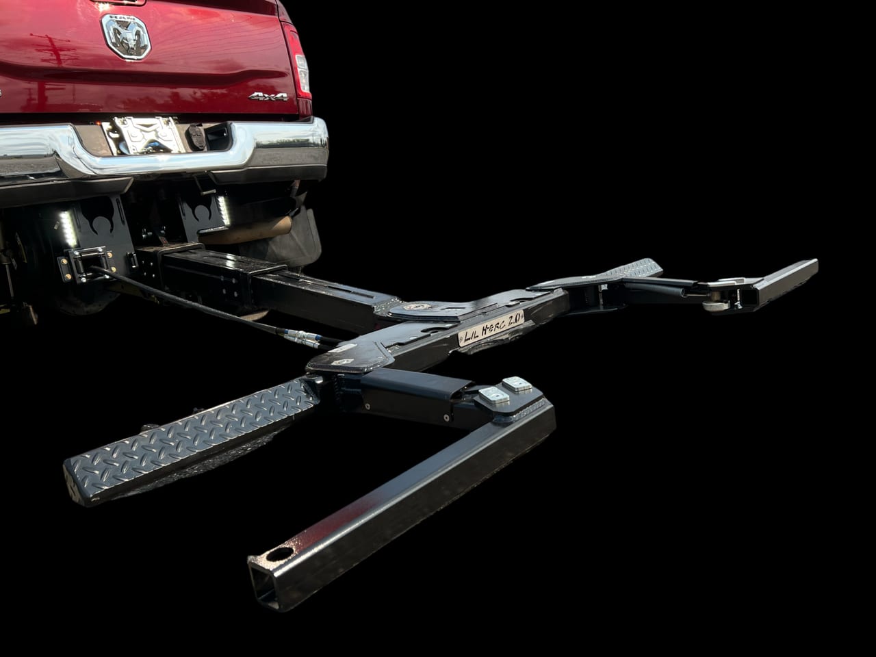 Lil Hercules wheel lift extended underneath a red pickup